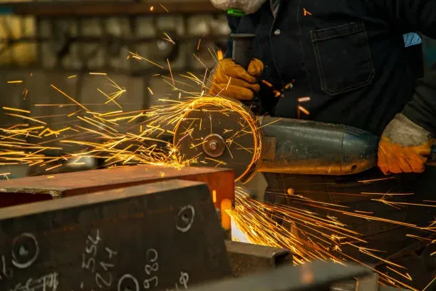 Mano firme guiando un disco de corte angular sobre una estructura metálica, manteniendo control y seguridad en el trabajo.