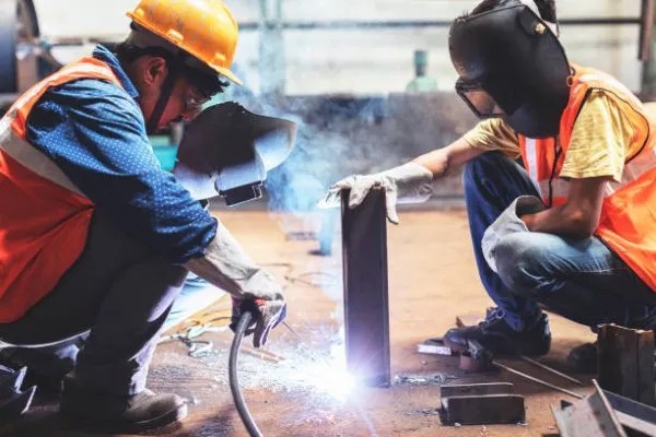 Dos hombres observando fallas comunes en soldadoras mientras supervisan el proceso de soldadura