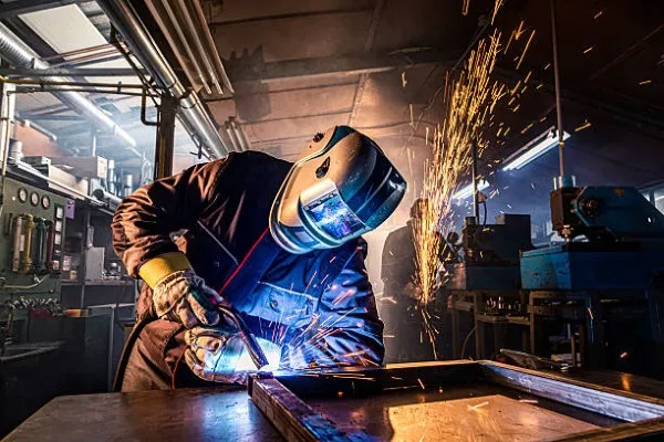 Trabajador realizando soldadura con electrodo en taller industrial